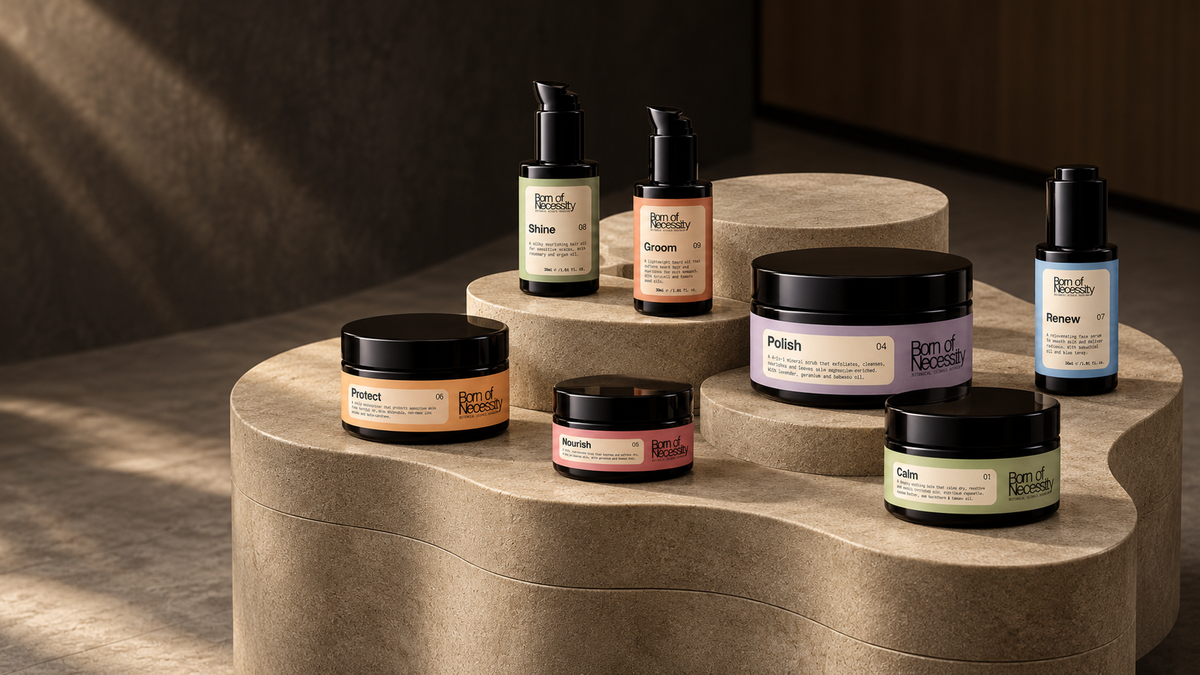 Born of Necessity skincare collection on a sculptural stone display, with seven products in their different jar and bottle sizes.