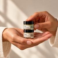 Calm and Restore 7g clear-glass mini balm jars stacked in two hands