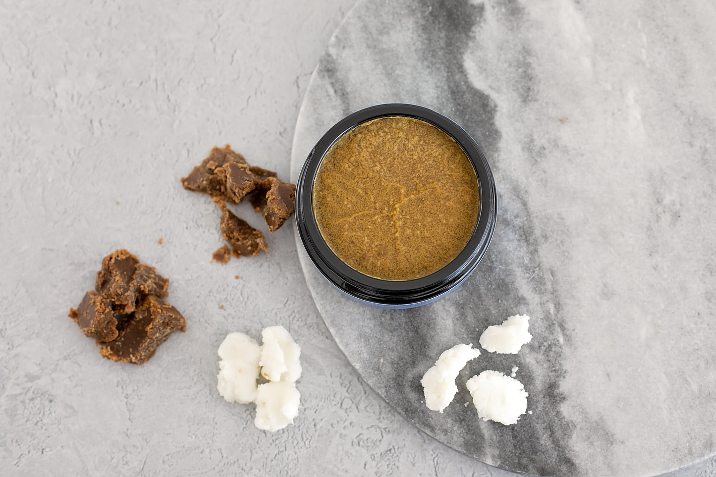 heal and restore healing cream for eczema & psoriasis prone skin, Heal & Restore Cream With Blue Chamomile in a jar surrounded by natural ingredients on a marble surface.