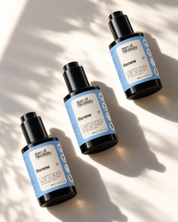Three Born of Necessity Renew serum bottles with blue labels in natural sunlight.