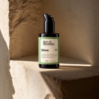 Shine rosemary and argan hair oil in a sunlit stone alcove.